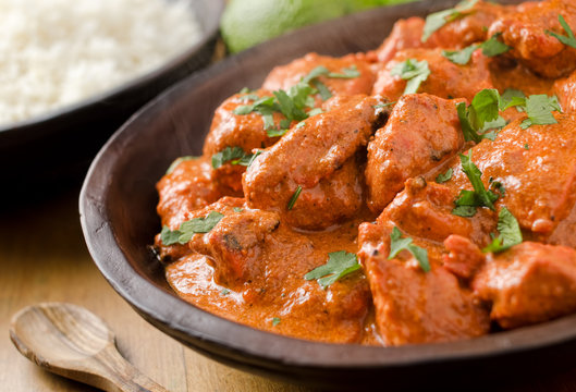 Plate of authentic butter chicken served with naan and garnished with fresh cream and coriander.